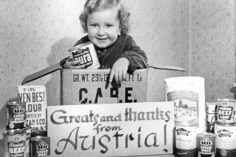 An Austrian girl poses with a "Thank You" sign after her family received a CARE package.